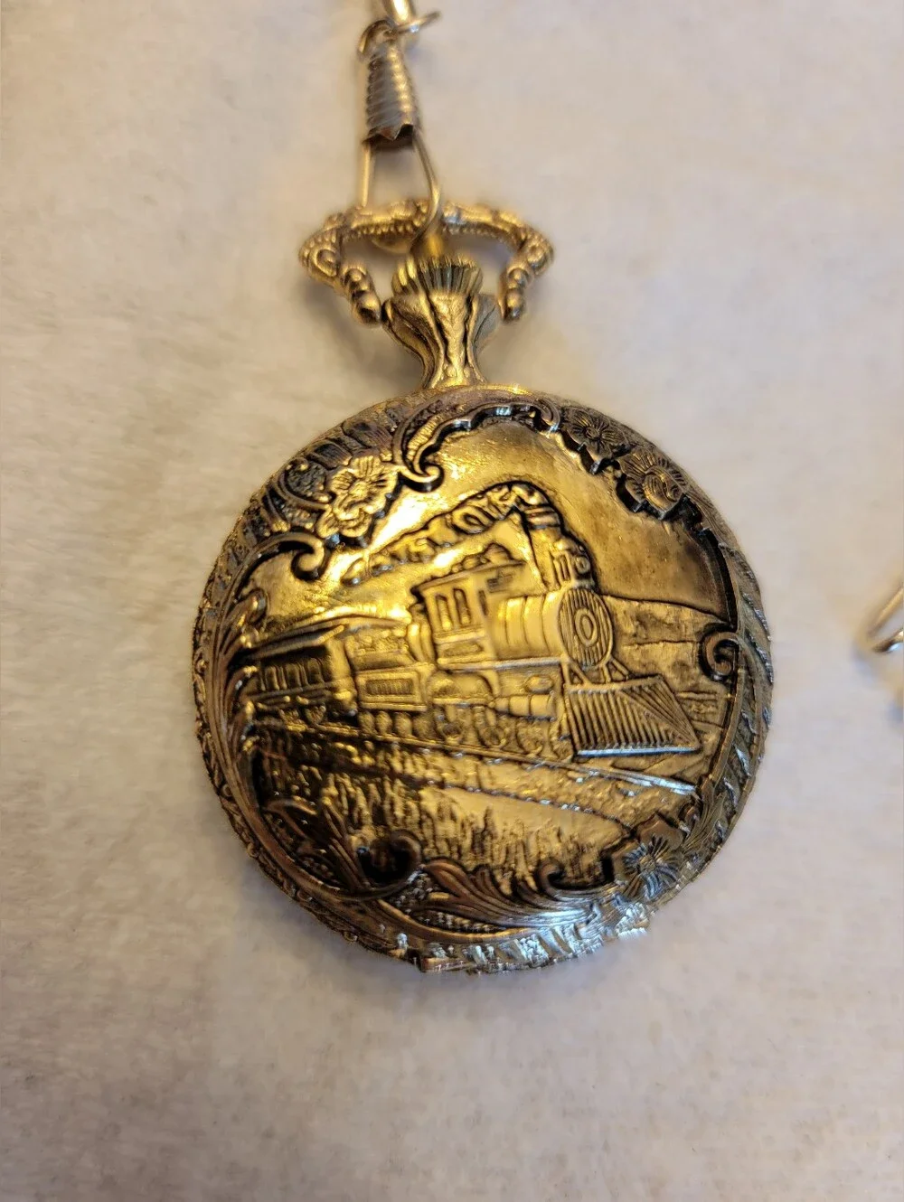 Vintage gold-tone pocket watch has a raised steam engine train motif.